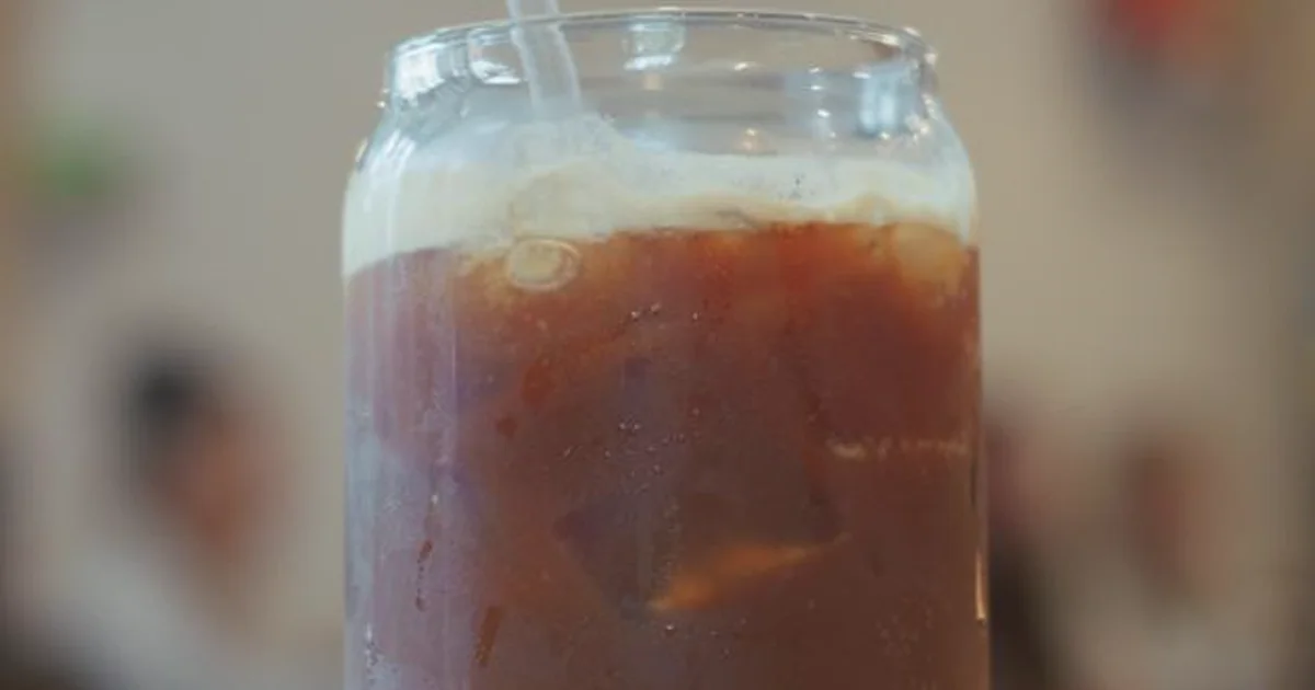 Vaso de cold brew frío con hielo sobre una mesa de madera